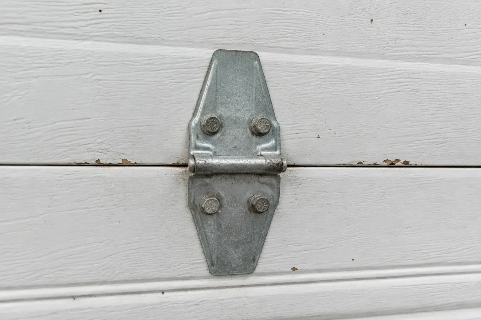 Metal center hinge across a seam in a white sectional garage door. — Garage Door Hinge Replacement, Mississauga