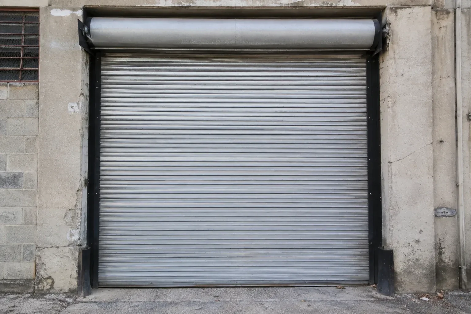 Closed metal rolling shutter in a weathered warehouse opening. — Commercial Rolling Door Repair, Mississauga